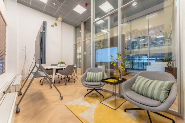 Moderne, licht ingerichte kantoorruimte aan de Weesperstraat 107 met vergadertafel, loungehoek en glazen wanden.