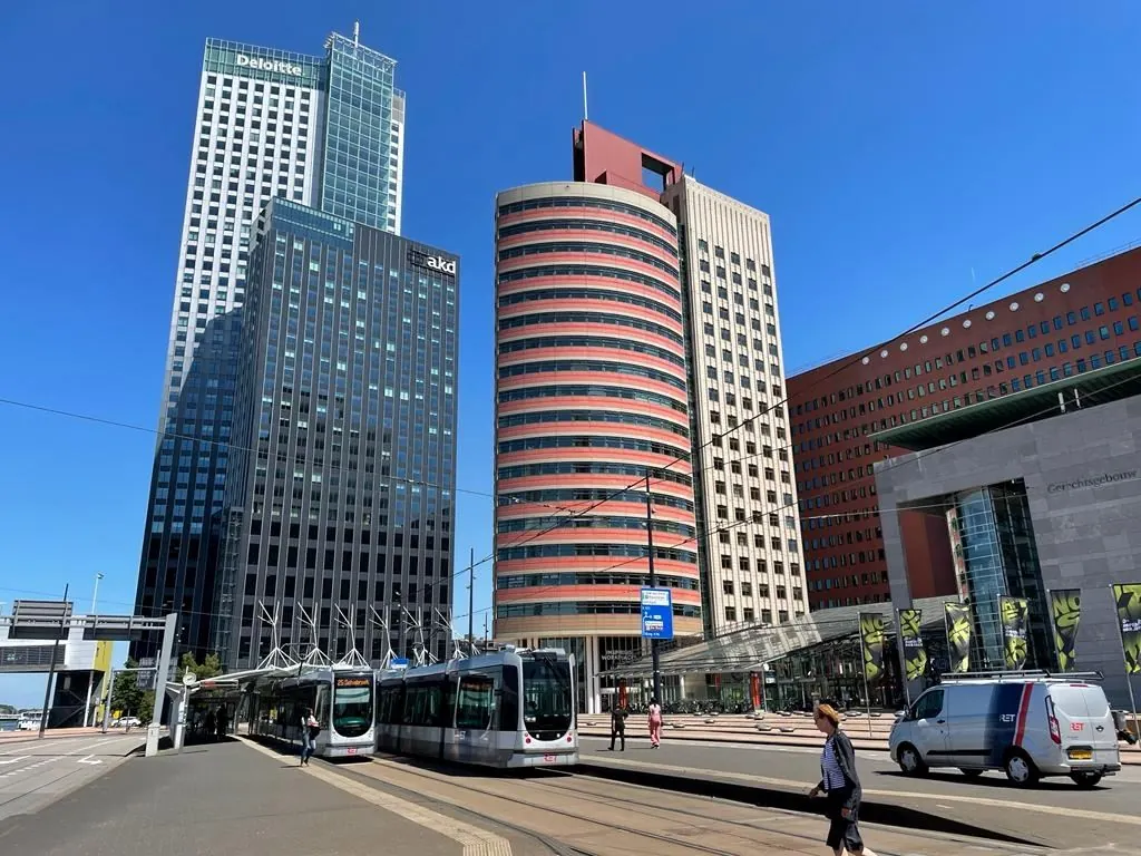 Kantoorpanden aan het Wilhelminaplein in Rotterdam met trams en voetgangers op de voorgrond.