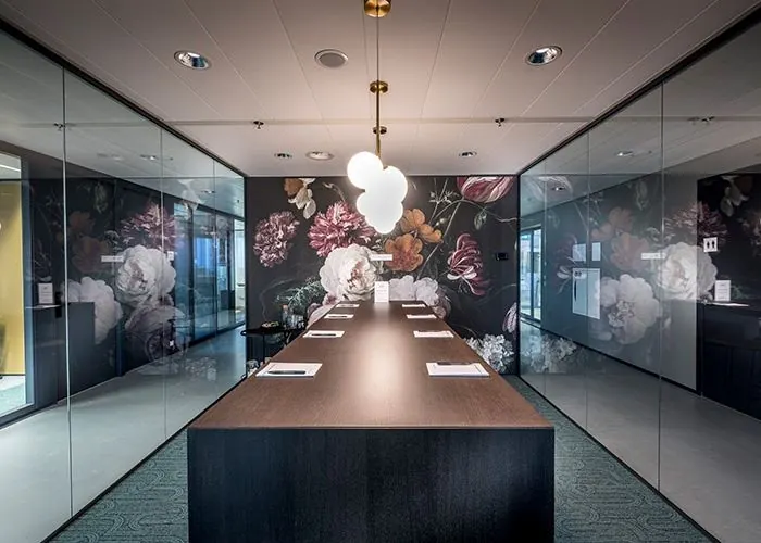 Stijlvolle vergaderruimte met glazen wanden en bloemenbehang in een kantoor aan het Wilhelminaplein 1 in Rotterdam.