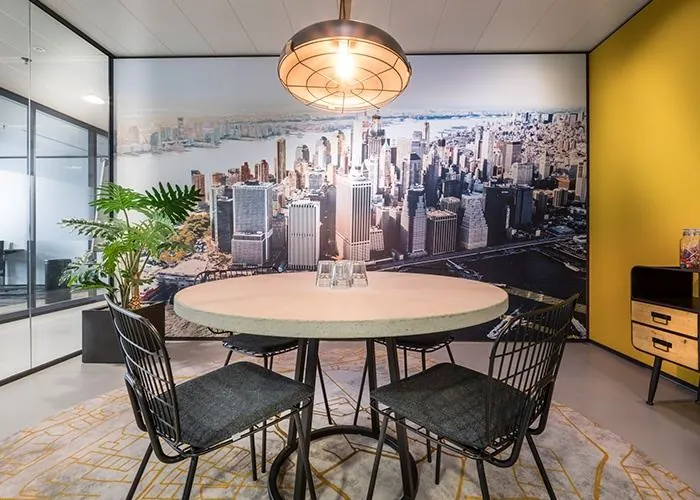 Moderne vergaderruimte in een kantoor op Wilhelminaplein 1 in Rotterdam met ronde tafel, vier stoelen en een wand met skylinefotobehang.