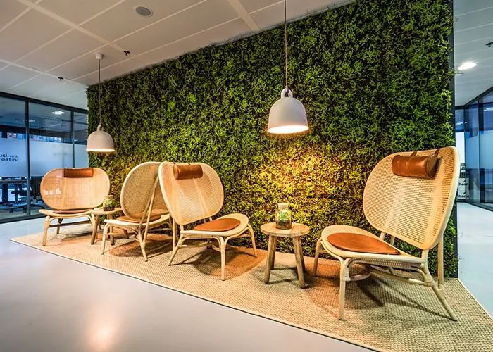 Moderne wachtruimte met rotan stoelen en groene moswand in een kantoorpand aan het Wilhelminaplein 1 in Rotterdam.