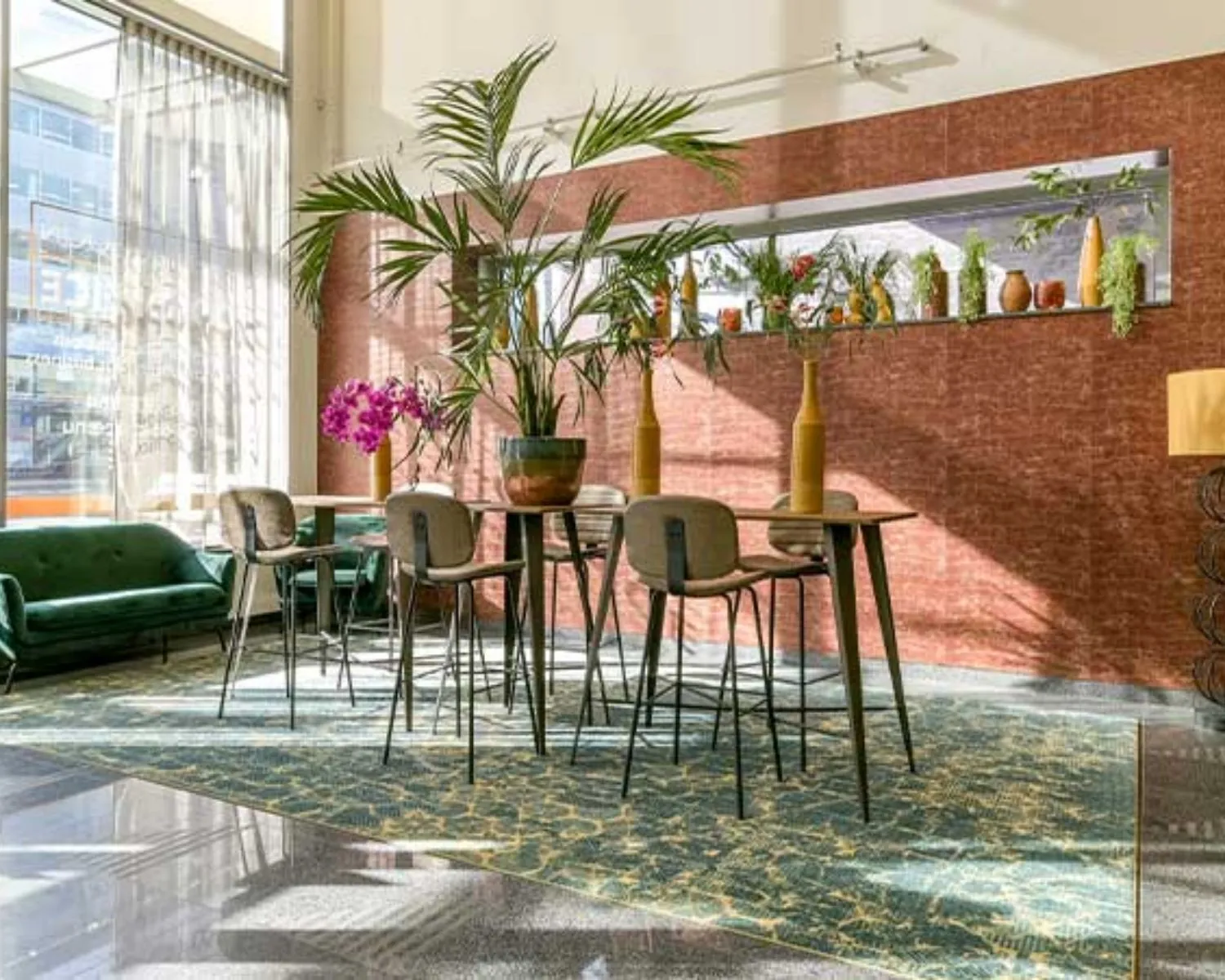 Moderne en lichte kantoorruimte aan het Bos en Lommerplein in Amsterdam met hoge ramen, groene planten en een gezellige zithoek.