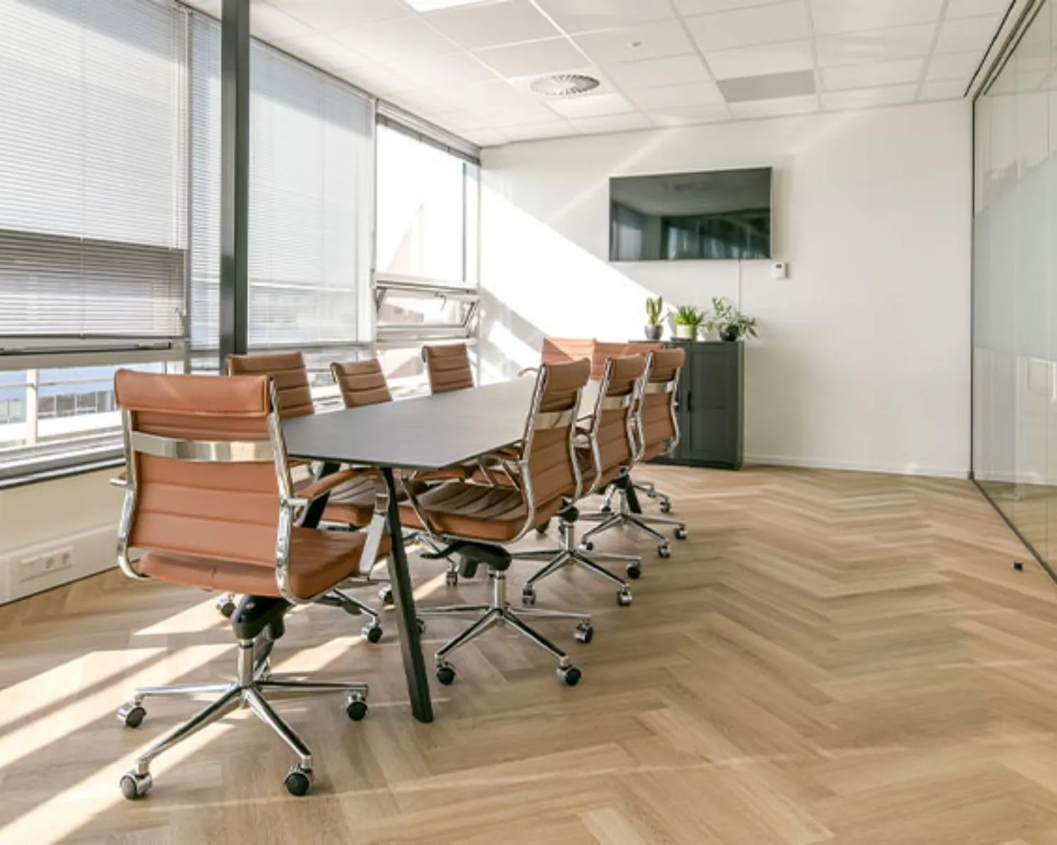 Moderne vergaderruimte met leren bureaustoelen en grote ramen in een kantoor aan het Bos en Lommerplein in Amsterdam.