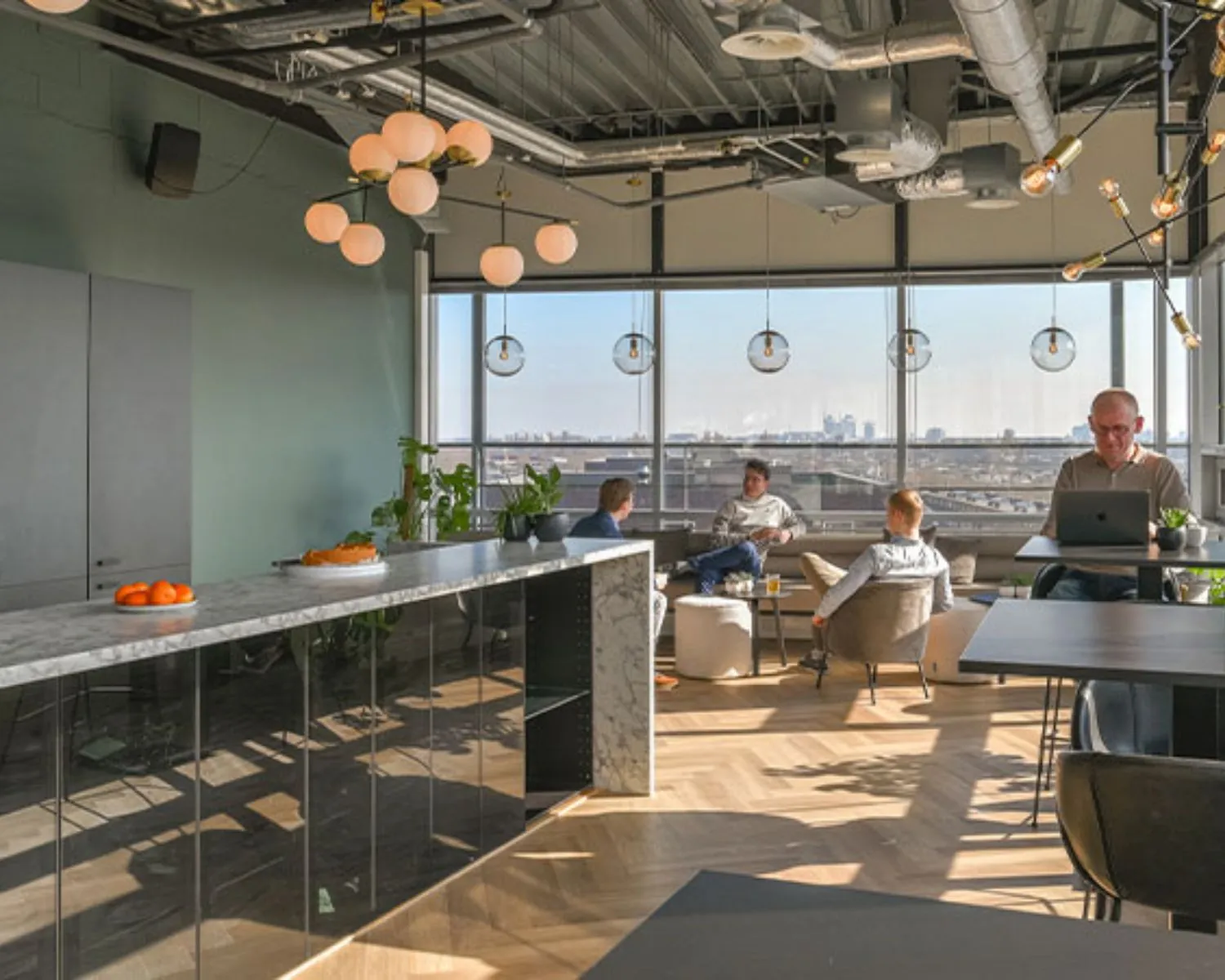 Moderne en lichte kantoorruimte aan het Bos en Lommerplein in Amsterdam met mensen die werken en overleggen in een comfortabele loungehoek.