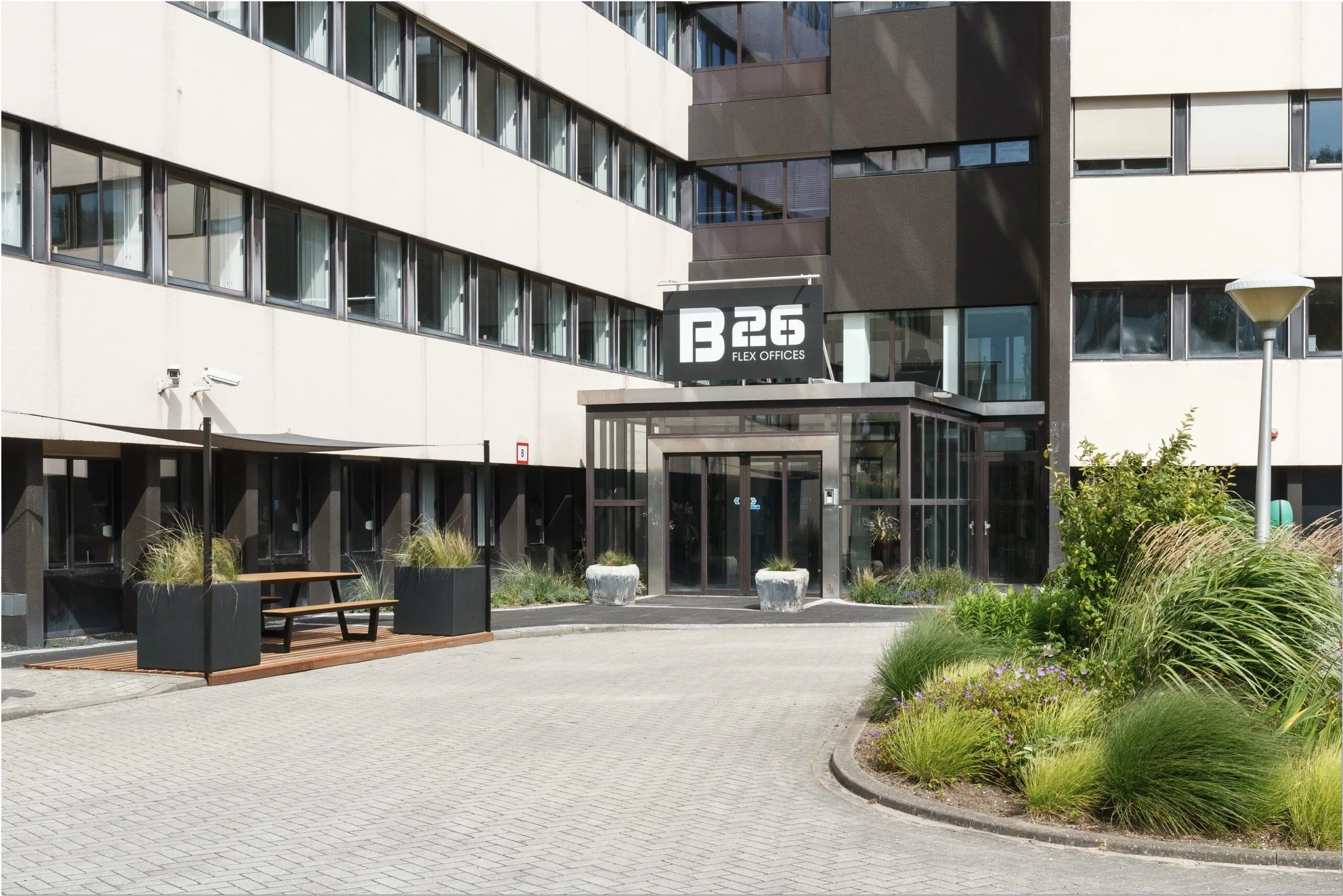 Ingang van B26 Flex Offices aan de Bredewater 26 in Zoetermeer met een nette buitenruimte en zitplek.