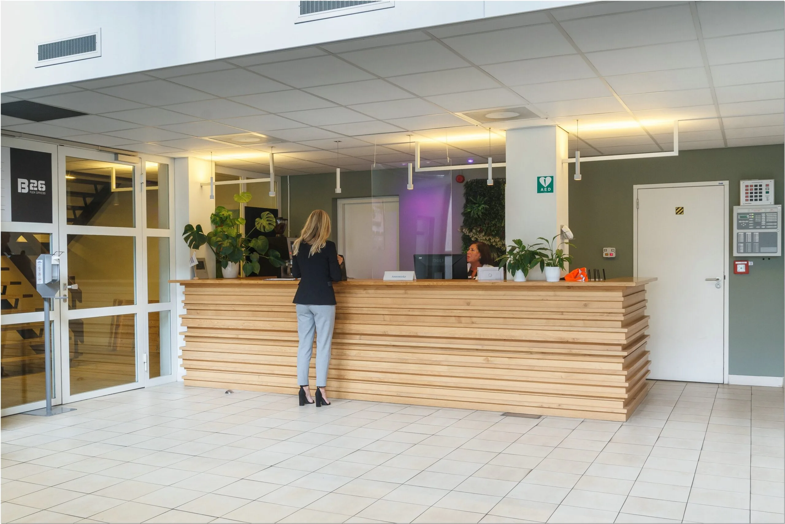 Receptiebalie met medewerker en bezoeker in de entree van kantoorpand Bredewater 26 in Zoetermeer.