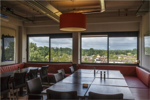 Vergaderruimte met grote ramen, uitzicht op groen en woningen vanaf Bredewater 26 in Zoetermeer.