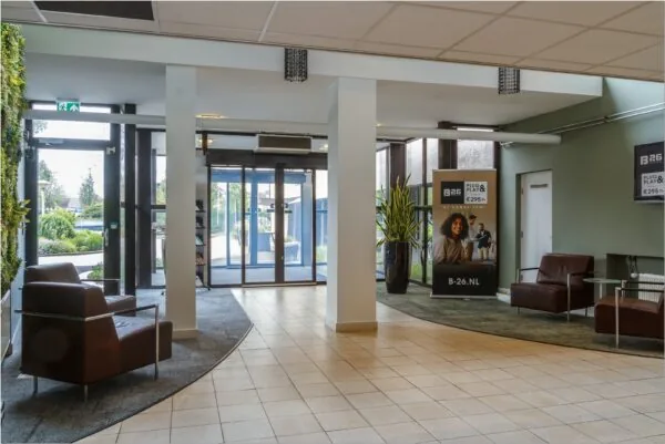 Moderne entreehal van kantoorpand Bredewater 26 in Zoetermeer met zitgelegenheid en promotiebord van B26.