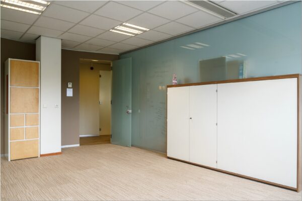 Moderne kantoorruimte in Bredewater 26, Zoetermeer met glazen wand, lichte vloerbedekking en kasten.
