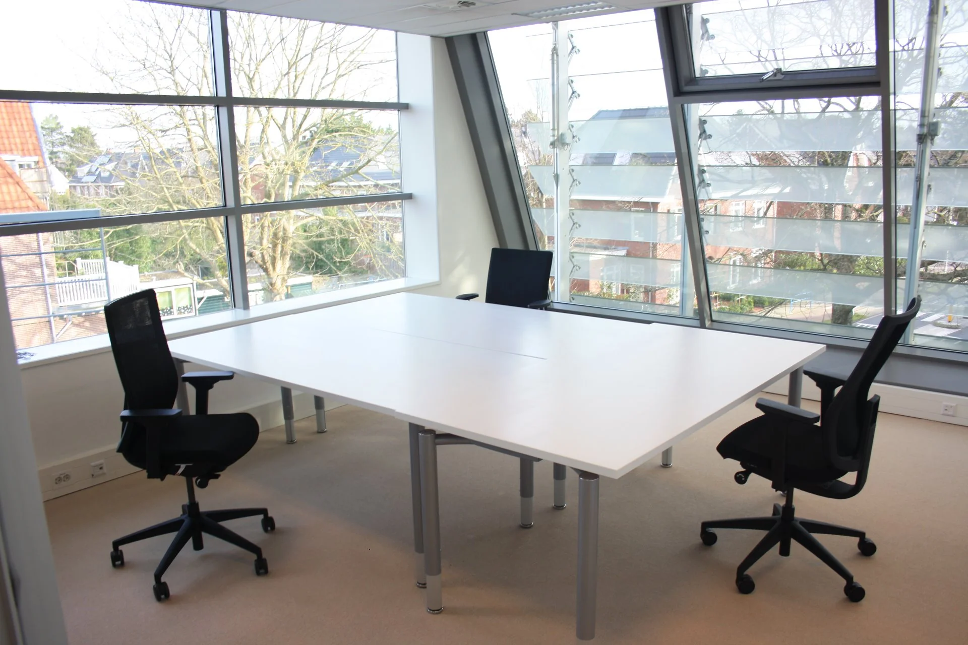 Moderne kantoorruimte aan de Bronsteeweg 10 in Heemstede met grote ramen en een vergadertafel met vier bureaustoelen.