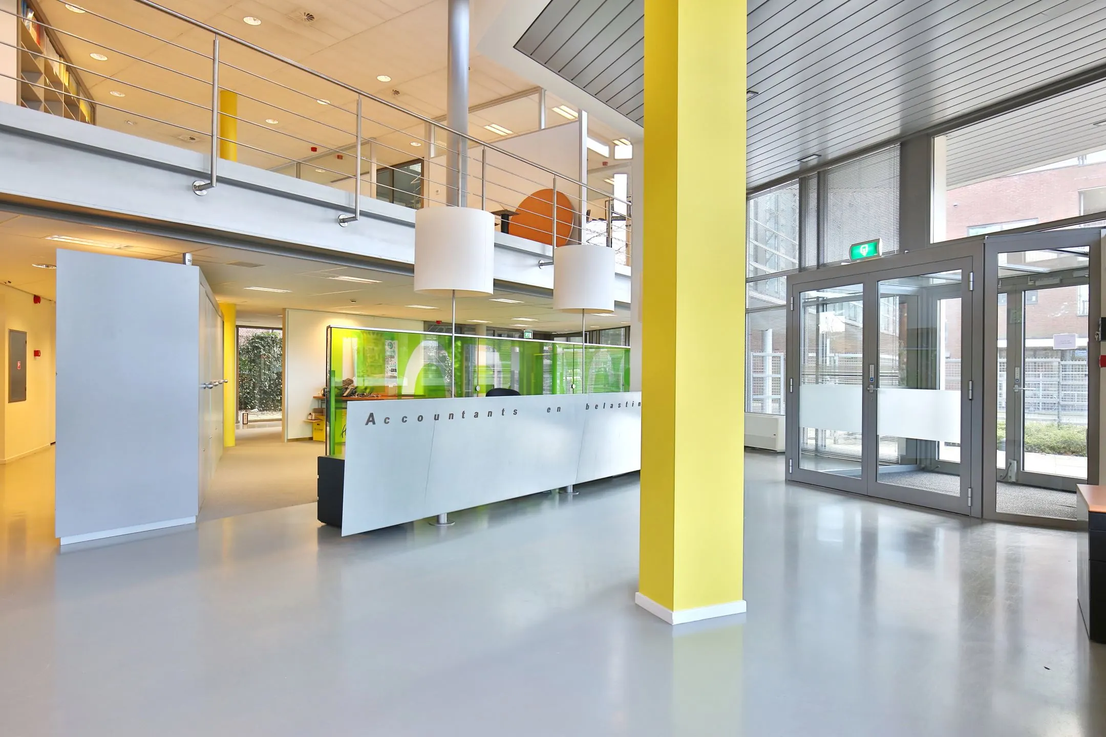 Moderne entree van een kantoorruimte aan de Bronsteeweg 10 in Heemstede met balie, glazen deuren en gele accenten.