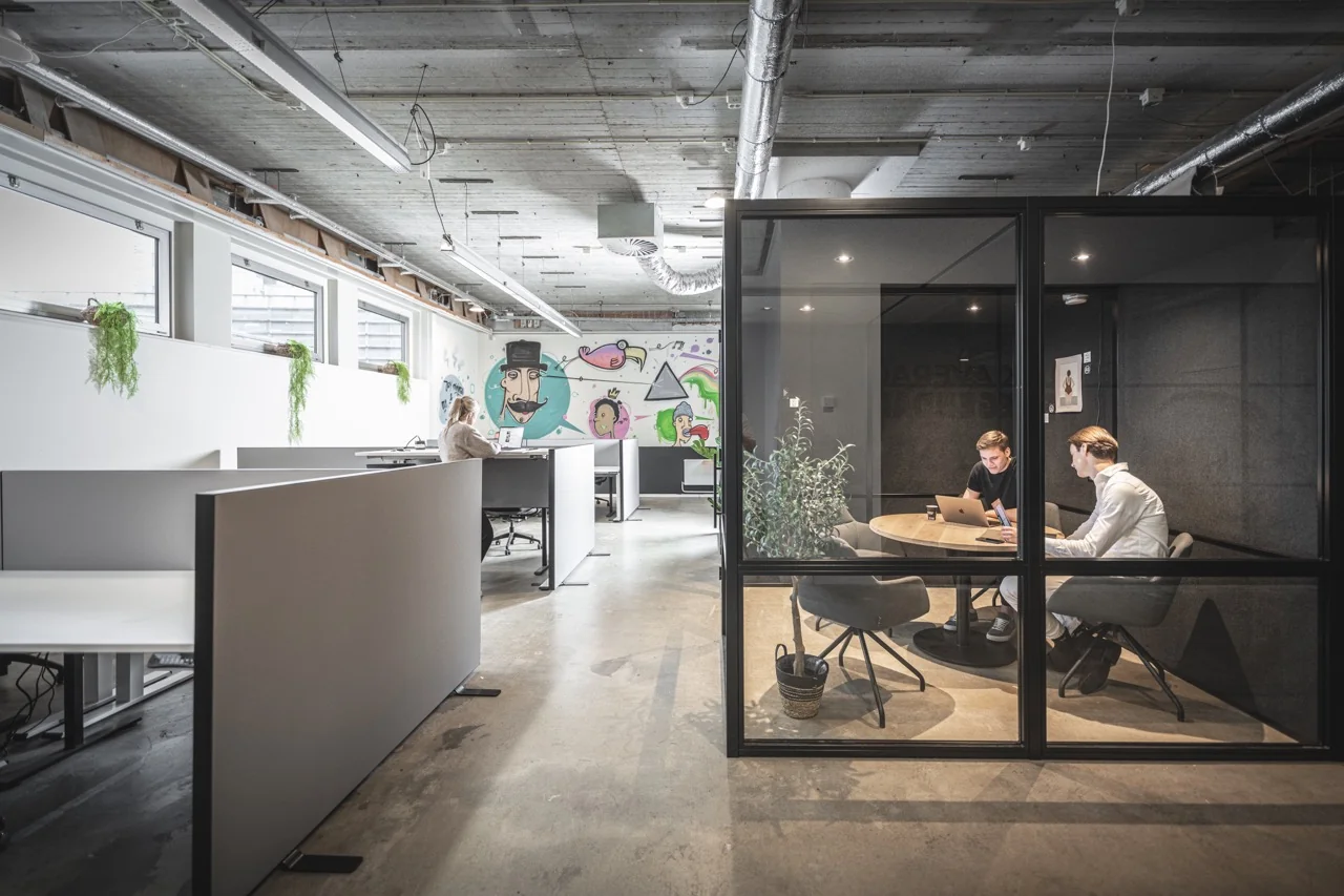 Moderne kantoorruimte aan de Brouwerijstraat 1 in Enschede met open werkplekken, vergaderruimte en creatieve muurschildering.