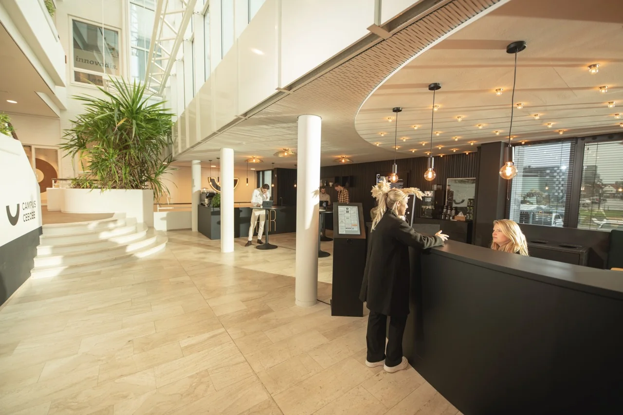 Moderne en lichte ontvangsthal van kantoorruimte aan de Brouwerijstraat 1 in Enschede met receptiebalie en zitgelegenheid.