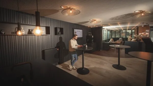 Moderne kantoorruimte aan de Brouwerijstraat 1 in Enschede met sta-tafels, sfeerverlichting en een loungegedeelte op de achtergrond.