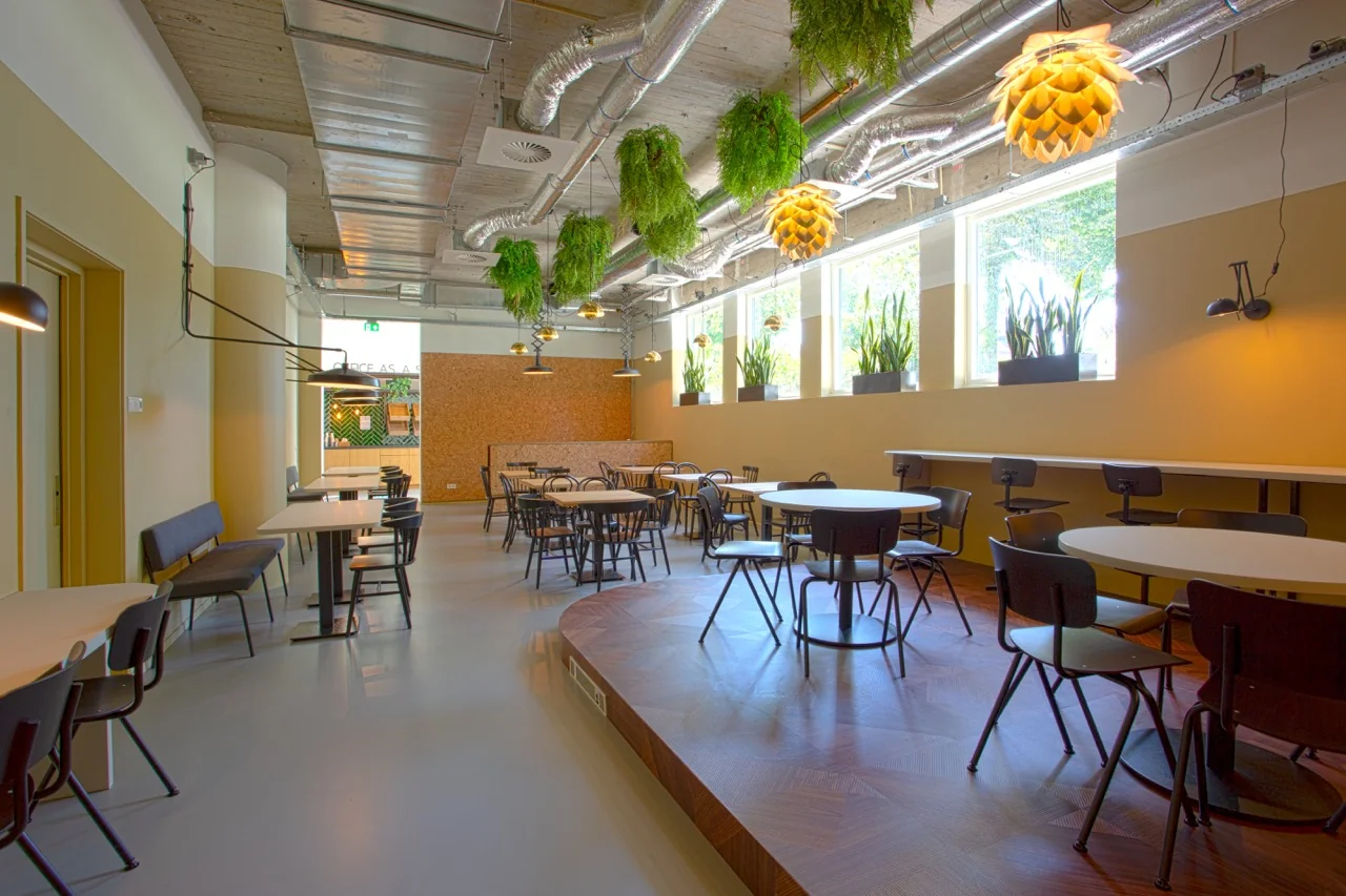 Moderne kantoorruimte aan de Brouwerijstraat 1 in Enschede met zithoeken, hangplanten en grote ramen voor natuurlijk licht.