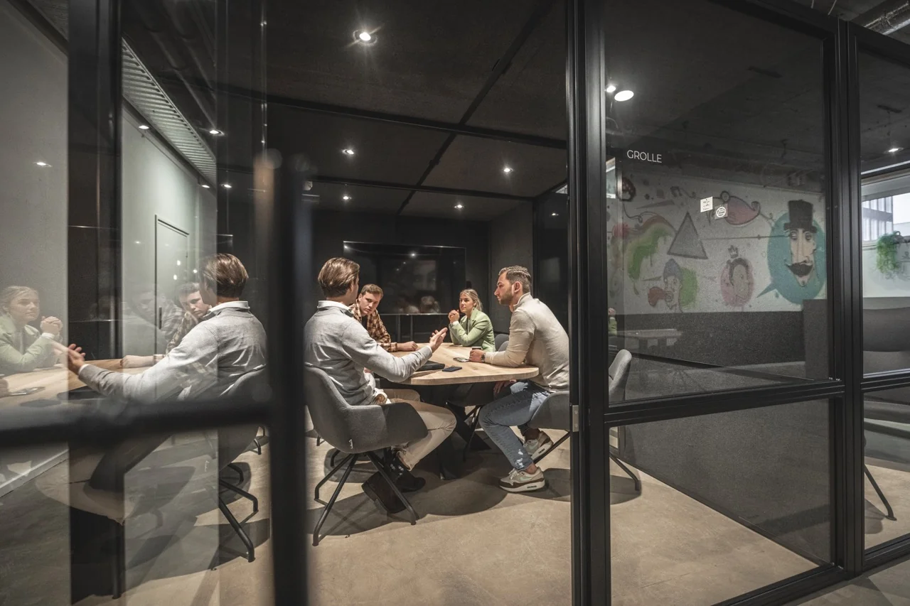 Vergaderruimte in modern kantoor aan de Brouwerijstraat 1 in Enschede, met vijf mensen in overleg.