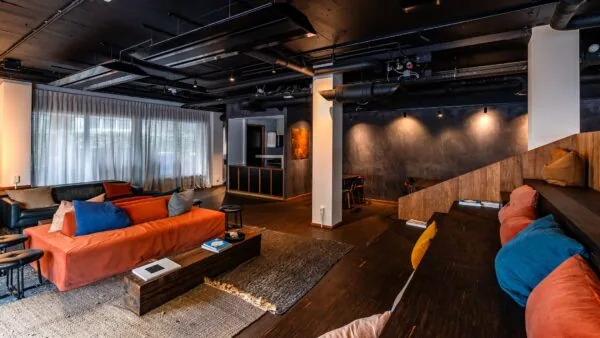 Stijlvolle en moderne kantoorruimte aan de Emmasingel 33 in Eindhoven met loungehoek, donkere houten vloer en zittribune met gekleurde kussens.