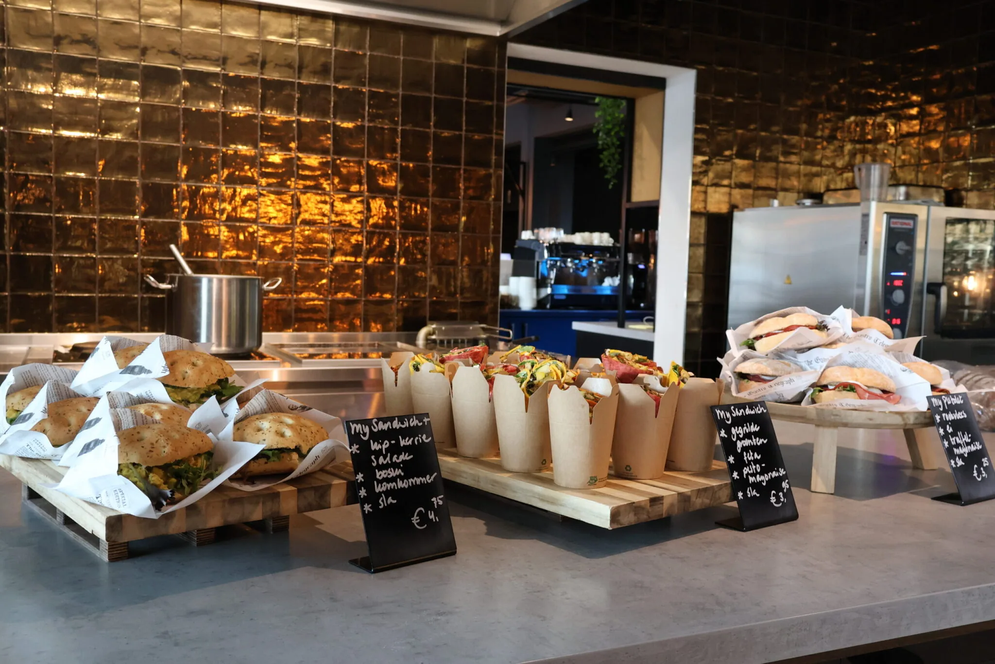 Een moderne lunchcounter in Flight Forum 760 Eindhoven met diverse vers belegde broodjes en wraps uitgestald op houten plateaus.