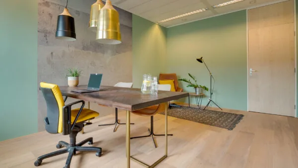 Modern ingerichte kantoorruimte met houten vloer, vergadertafel, gele bureaustoel en groene accentmuur in Flight Forum 760 in Eindhoven.