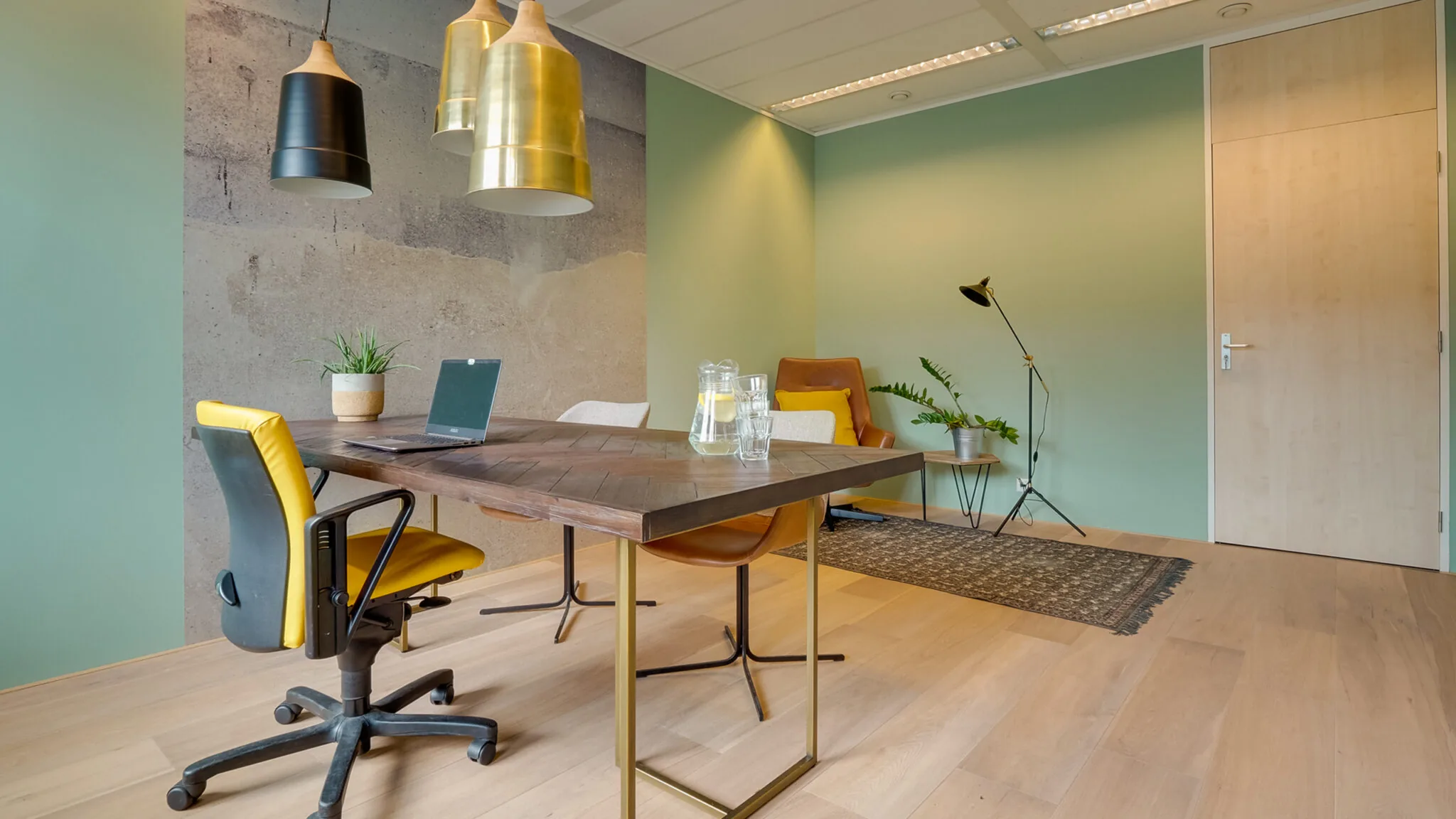 Modern ingerichte kantoorruimte met houten vloer, vergadertafel, gele bureaustoel en groene accentmuur in Flight Forum 760 in Eindhoven.
