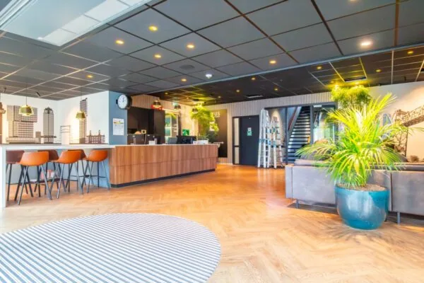 Moderne, lichte ontvangsthal van een kantoorruimte aan George Hintzenweg 89 in Rotterdam met een balie, zitgedeelte en groene accenten.