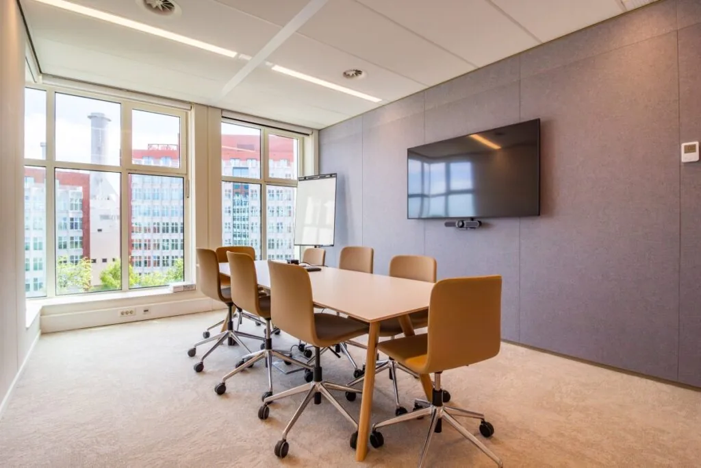 Moderne vergaderruimte met zes stoelen, een flatscreen en uitzicht op kantoren aan de George Hintzenweg 89 in Rotterdam.