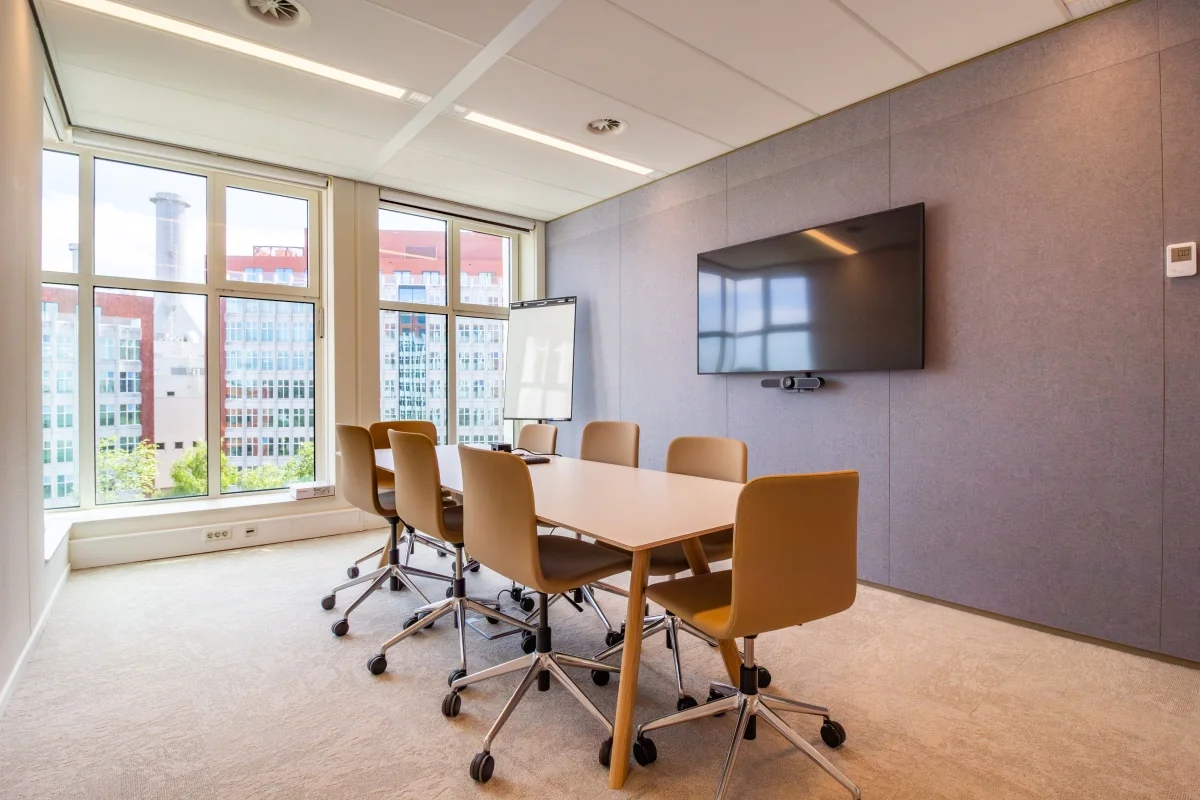 Moderne vergaderruimte met zes stoelen, een flatscreen en uitzicht op kantoren aan de George Hintzenweg 89 in Rotterdam.