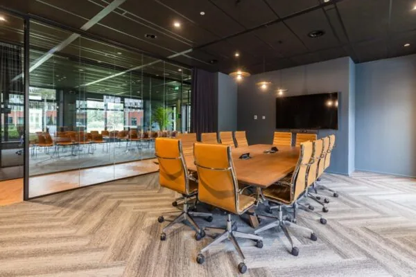 Moderne vergaderruimte met leren stoelen, grote houten tafel en glazen wand in kantoor aan George Hintzenweg 89 in Rotterdam.