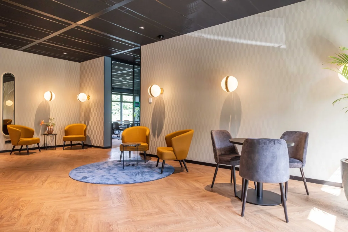 Moderne wachtruimte in een kantoor aan de George Hintzenweg 89 in Rotterdam met gele en grijze zitmeubelen en houten vloer.