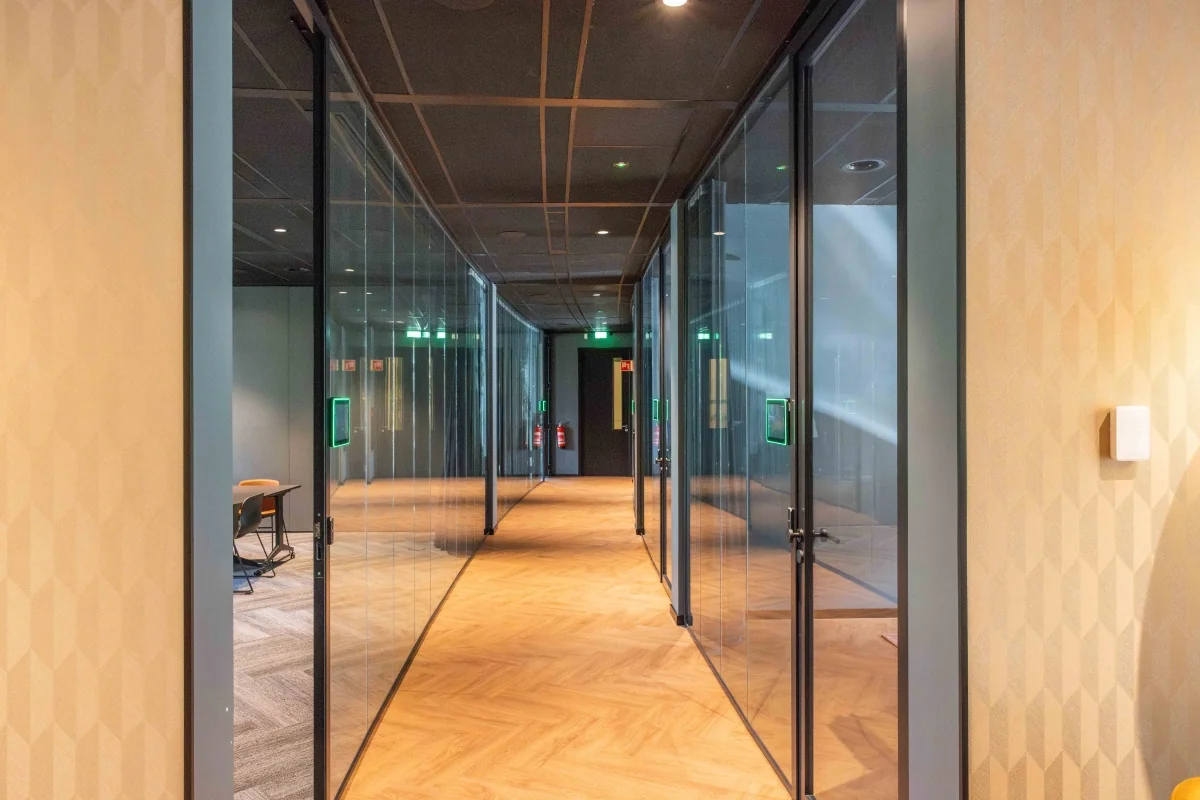 Moderne gang met glazen kantoorruimtes in een kantoorpand aan de George Hintzenweg 89 in Rotterdam.