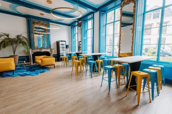 Stijlvolle kantoorruimte aan de Kromme Nieuwegracht in Utrecht met felgekleurde zitplaatsen, hoge tafels en klassieke details.