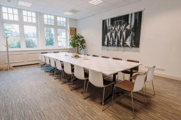 Vergaderruimte met lange tafel, moderne stoelen en grote ramen aan de Kromme Nieuwe Gracht in Utrecht.