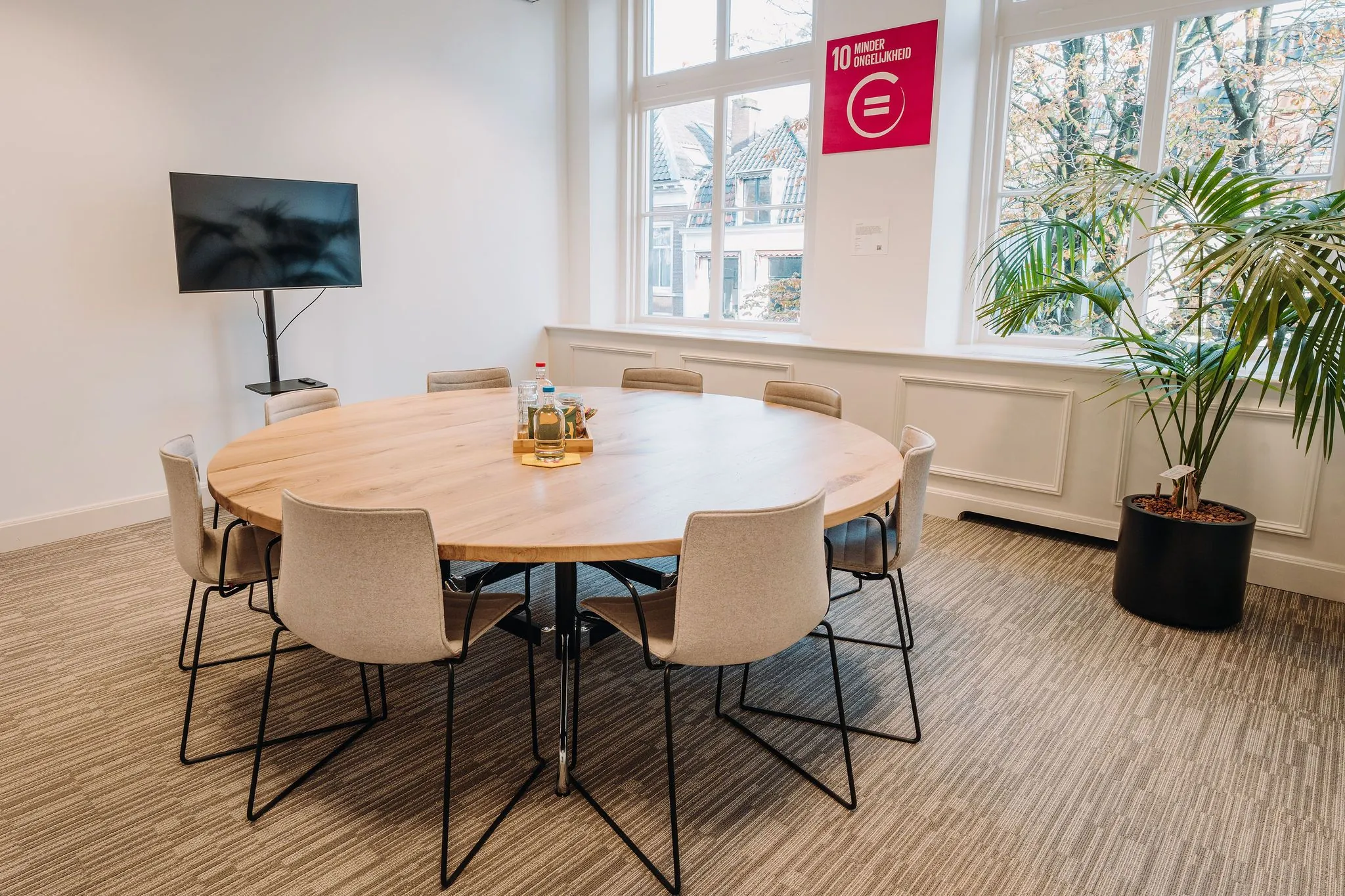 Moderne vergaderruimte aan de Kromme Nieuwe Gracht in Utrecht met ronde tafel, acht stoelen, flatscreen en grote ramen.