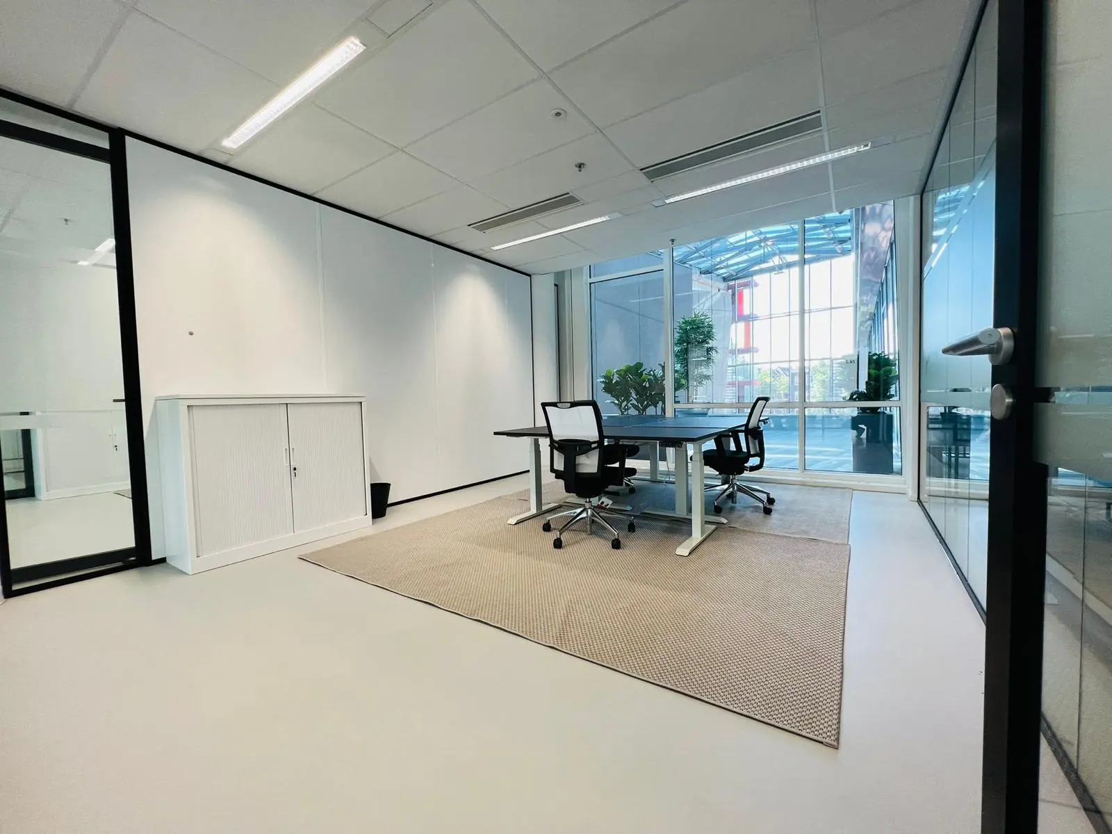 Moderne kantoorruimte met glazen wanden en twee bureaustoelen aan een tafel op het Kruisplein 480 in Rotterdam.