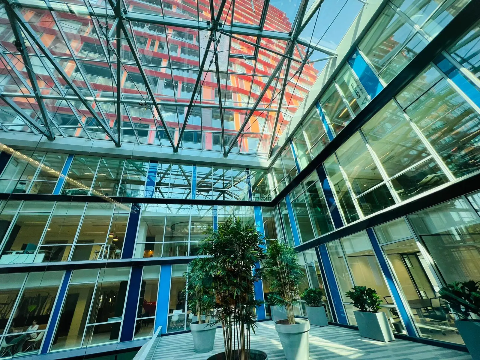 Moderne glazen binnentuin van een kantoorgebouw aan het Kruisplein 480 in Rotterdam met veel natuurlijk licht en groene planten.