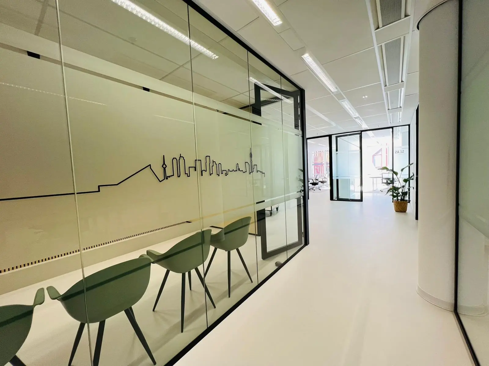 Moderne kantoorruimte aan het Kruisplein in Rotterdam met glazen wanden, wachtruimte en skyline-decoratie.