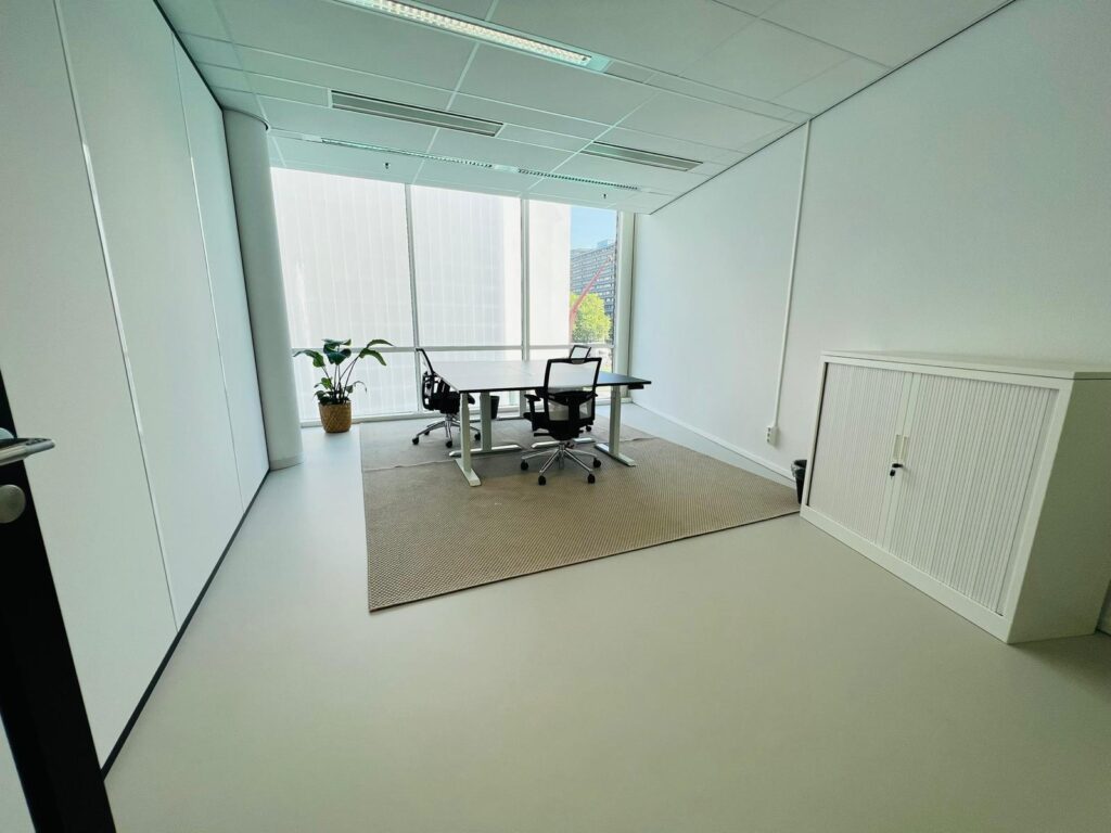 Moderne, lichte kantoorruimte aan het Kruisplein 480 in Rotterdam met bureau, stoelen, kast en grote ramen.