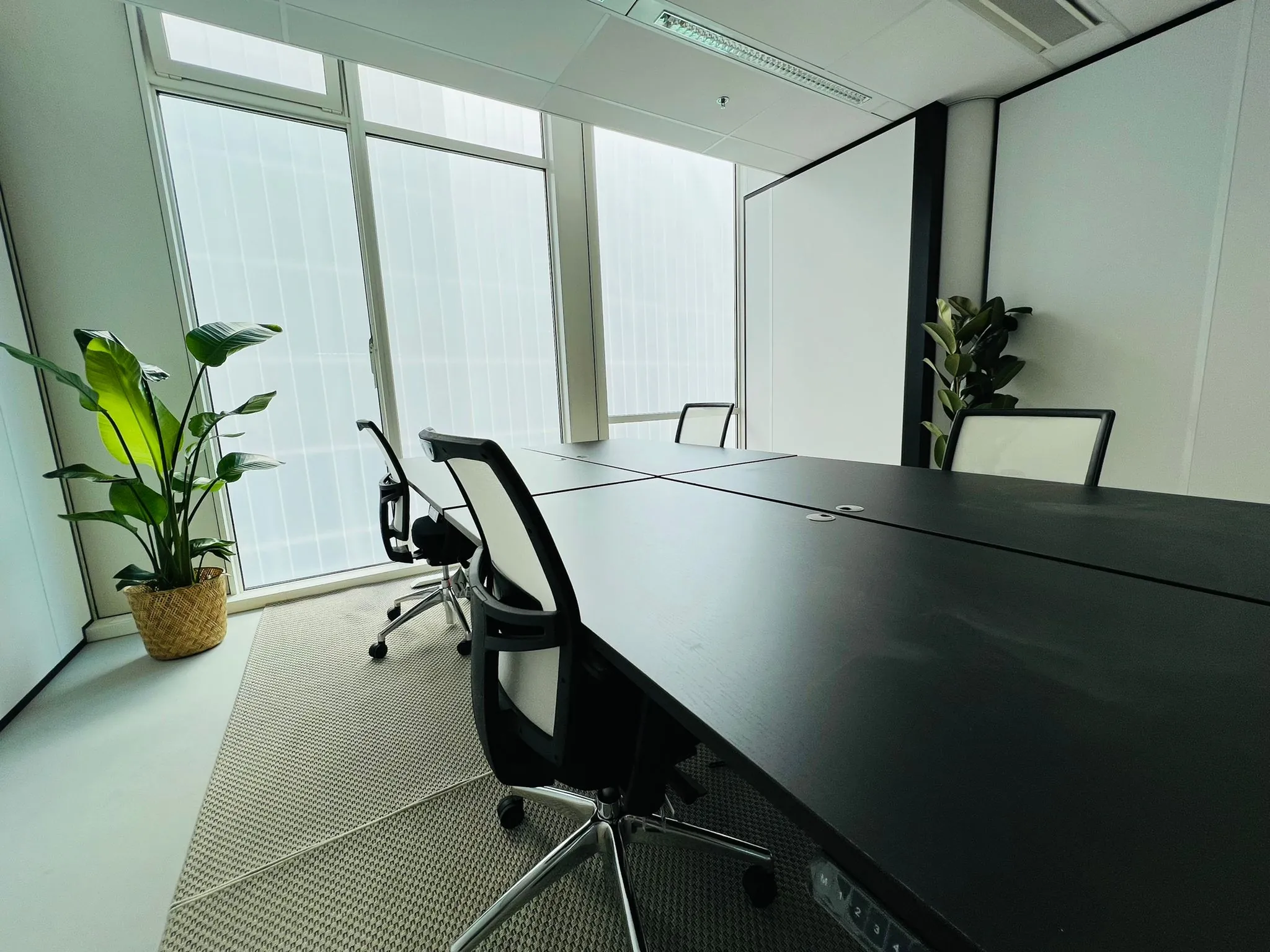 Moderne vergaderruimte met zwarte tafel, ergonomische stoelen en grote ramen in kantoor aan het Kruisplein 480 in Rotterdam.
