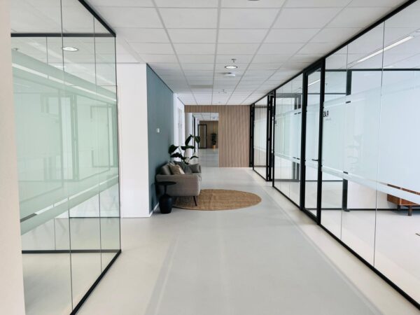 Moderne kantoorruimte aan het Kruisplein 480 in Rotterdam met glazen wanden en een loungehoek.
