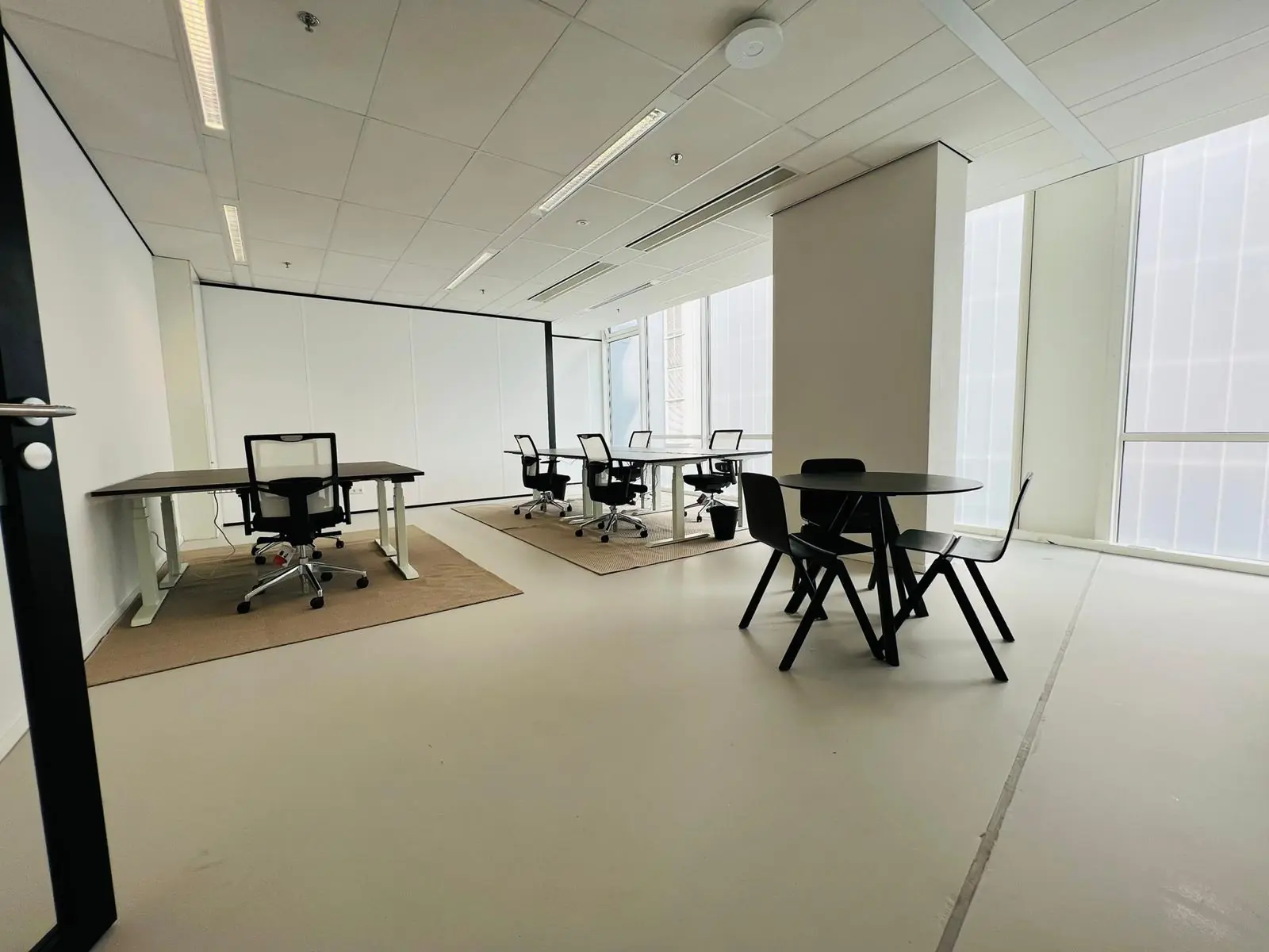 Moderne, lichte kantoorruimte met bureaus en vergadertafel aan het Kruisplein 480 in Rotterdam.