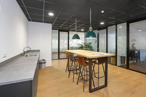 Moderne kantoorruimte aan de Meander 251 in Arnhem met een open keuken, hoge tafel en glazen vergaderruimtes.
