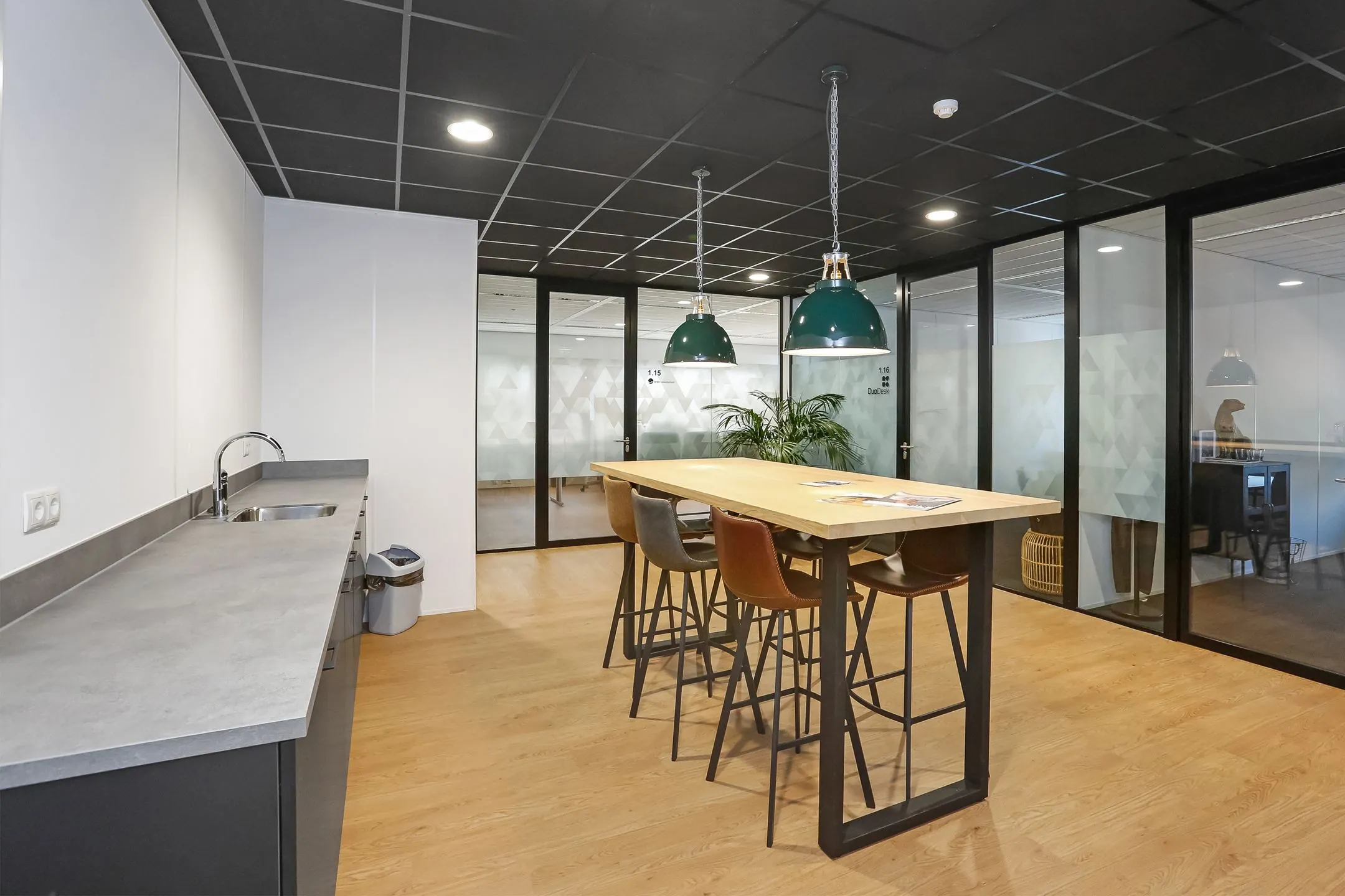 Moderne kantoorruimte aan de Meander 251 in Arnhem met een open keuken, hoge tafel en glazen vergaderruimtes.