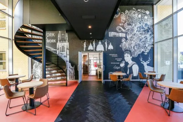 Moderne kantoorruimte aan de Meander 251 in Arnhem met een opvallende muurschildering, ronde zitjes en een zwarte wenteltrap.