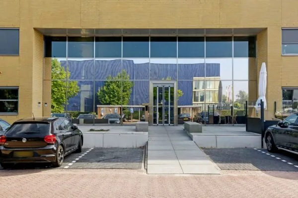Entree van het kantoorpand aan Meander 251 in Arnhem met grote glazen gevel en parkeergelegenheid.