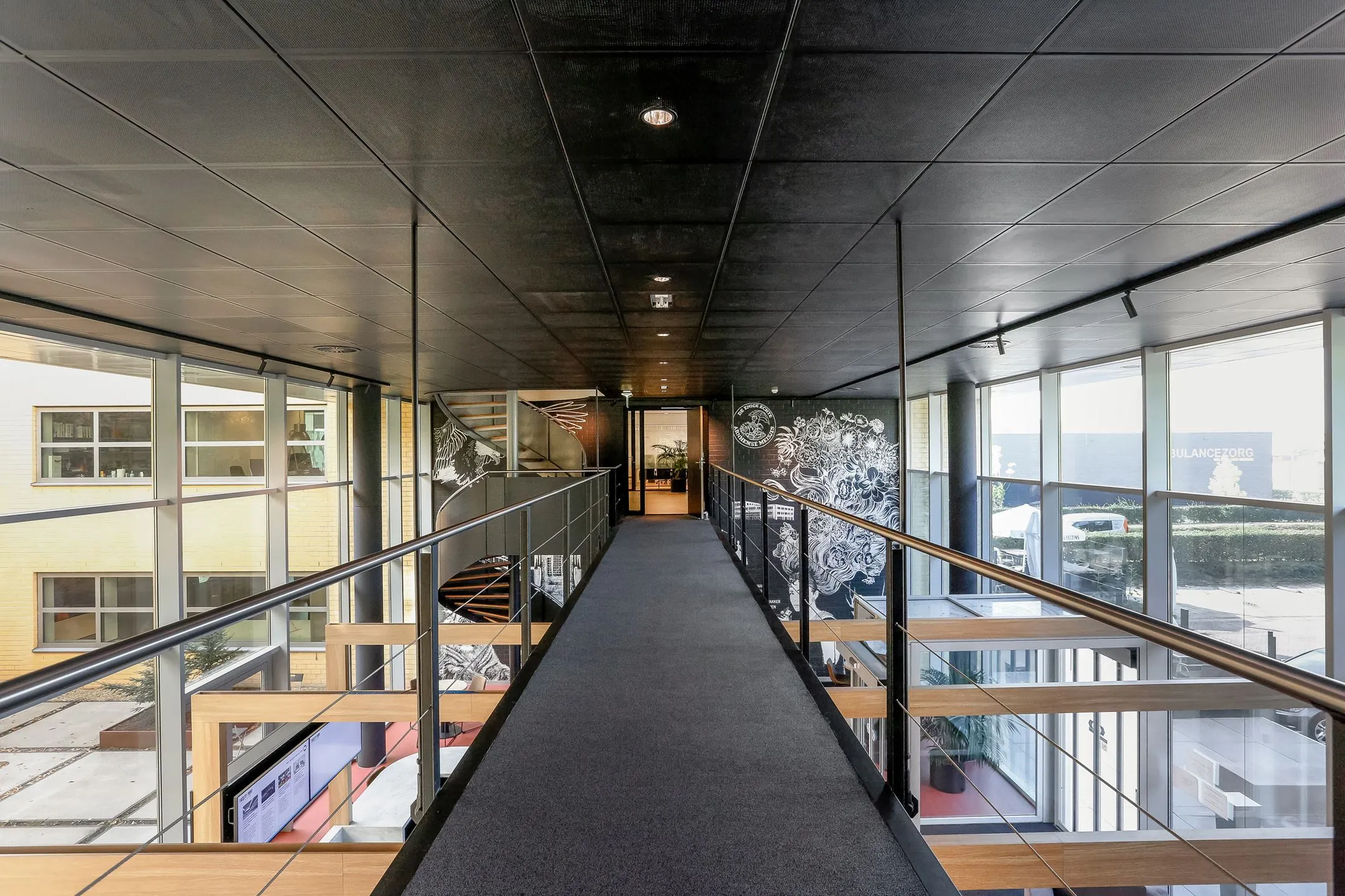 Licht en modern interieur van een kantoorruimte aan de Meander 251 in Arnhem met glazen wanden en een overlopende loopbrug.