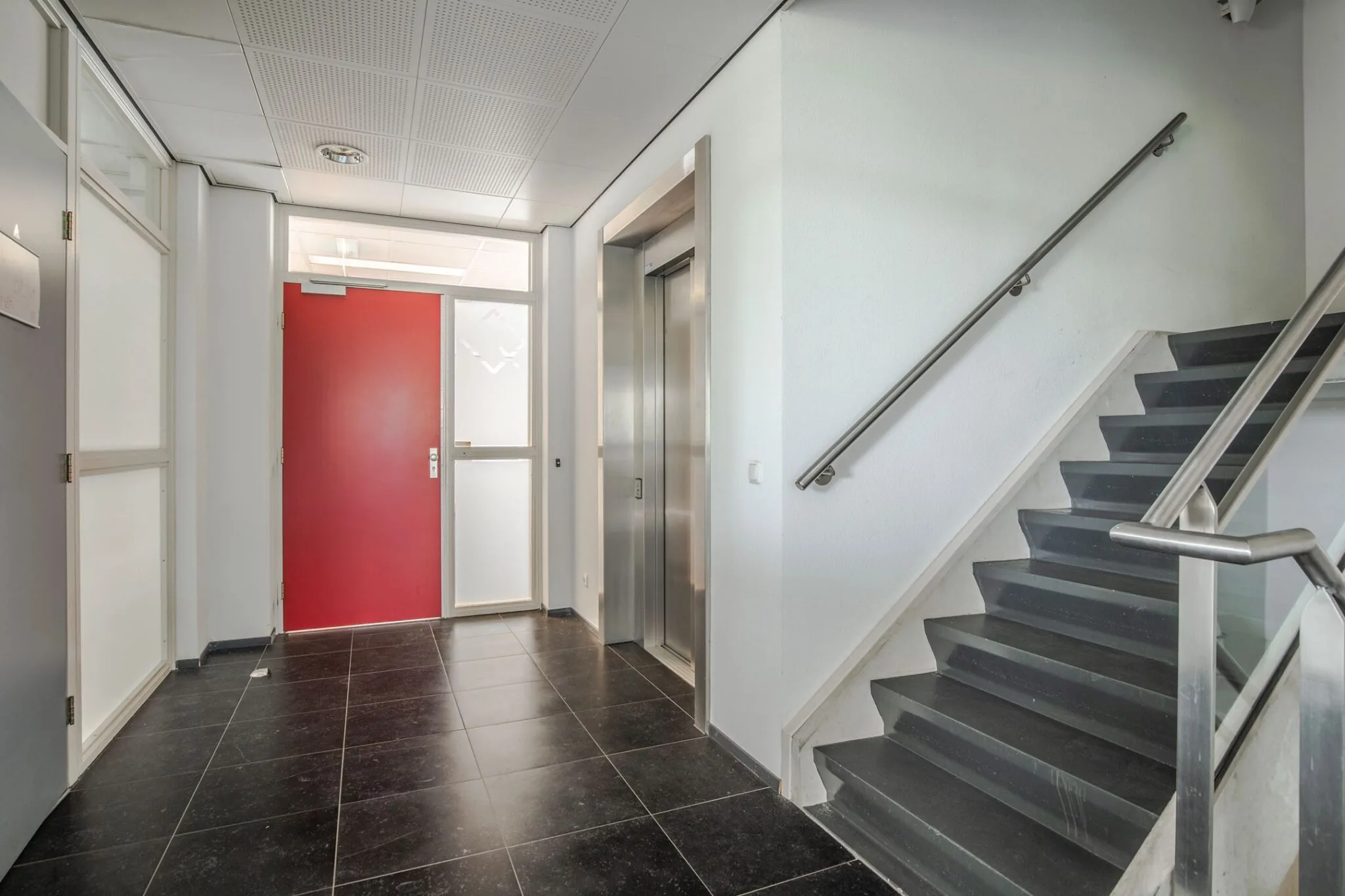 Moderne entree van kantoorpand Mercurion 24 in Zevenaar met trap, lift en rode deur.