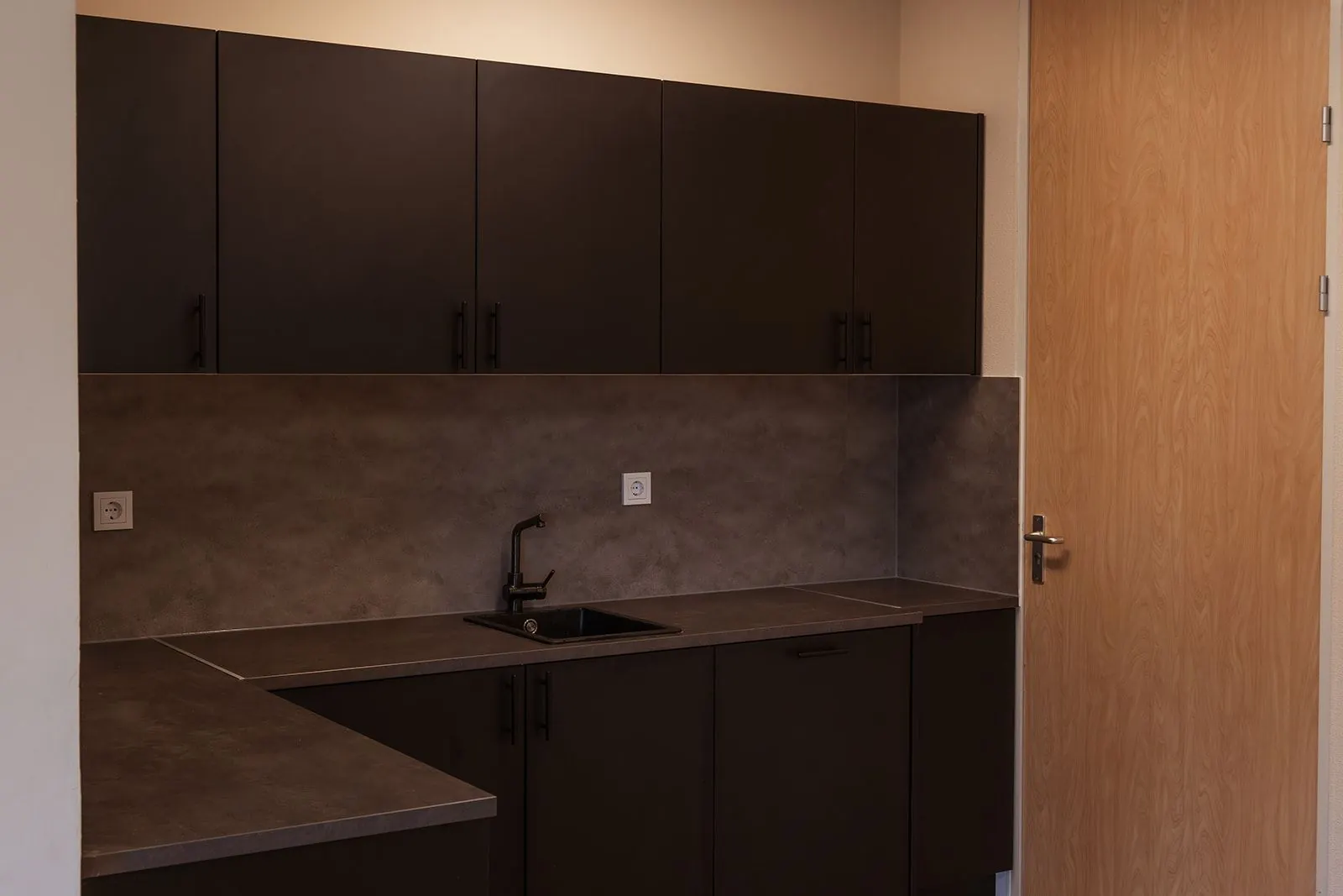 Moderne pantry met donker keukenblok en matzwarte kraan in kantoorruimte Mercurion 24 in Zevenaar.