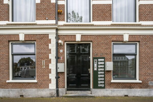 Voorgevel van het kantoorpand aan de Nieuwe Gracht 45-47 in Haarlem met zwarte voordeur en brievenbussen.