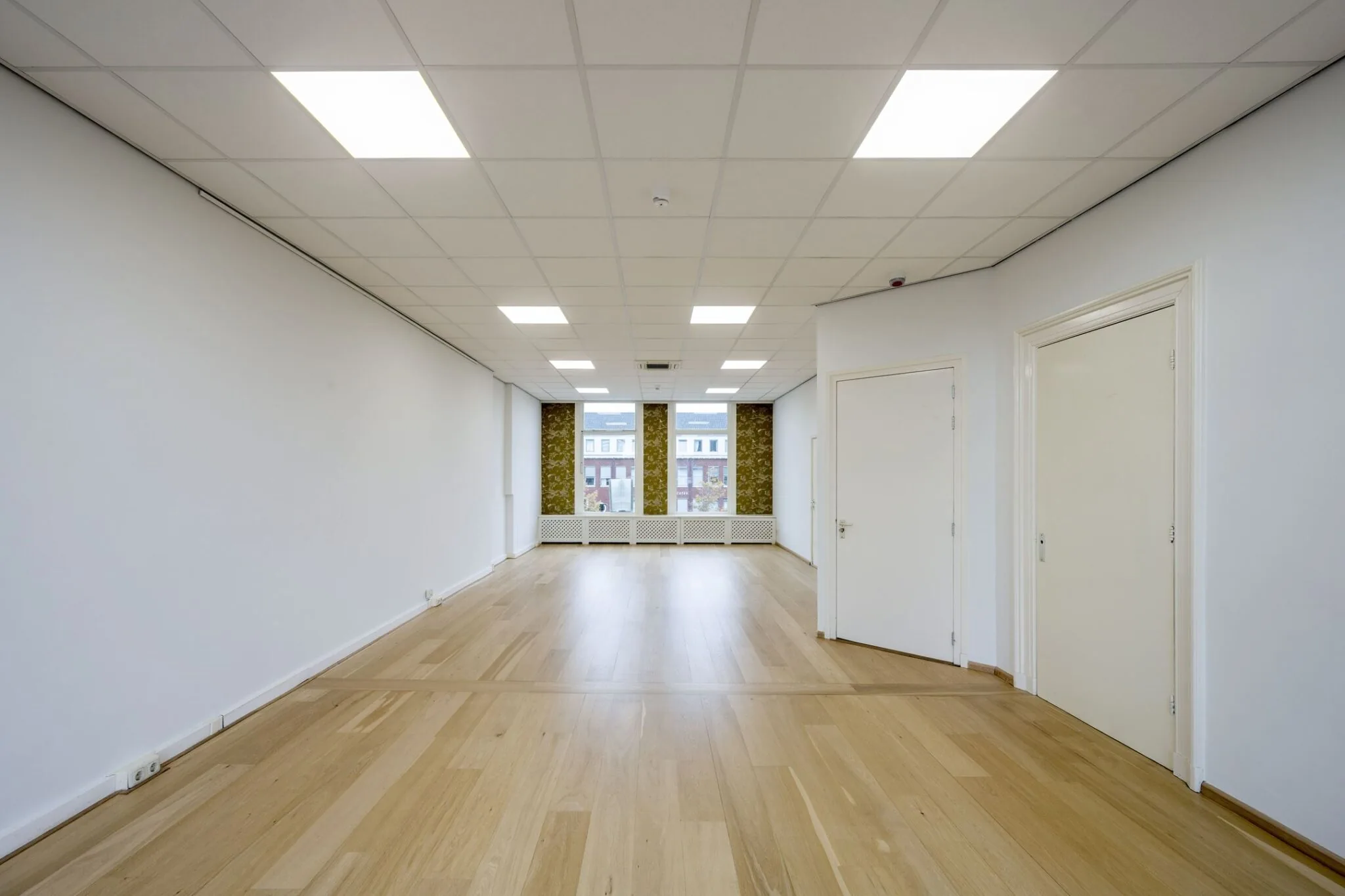 Lichte, lege kantoorruimte met houten vloer en grote ramen aan de Nieuwe Gracht 45-47 in Haarlem.