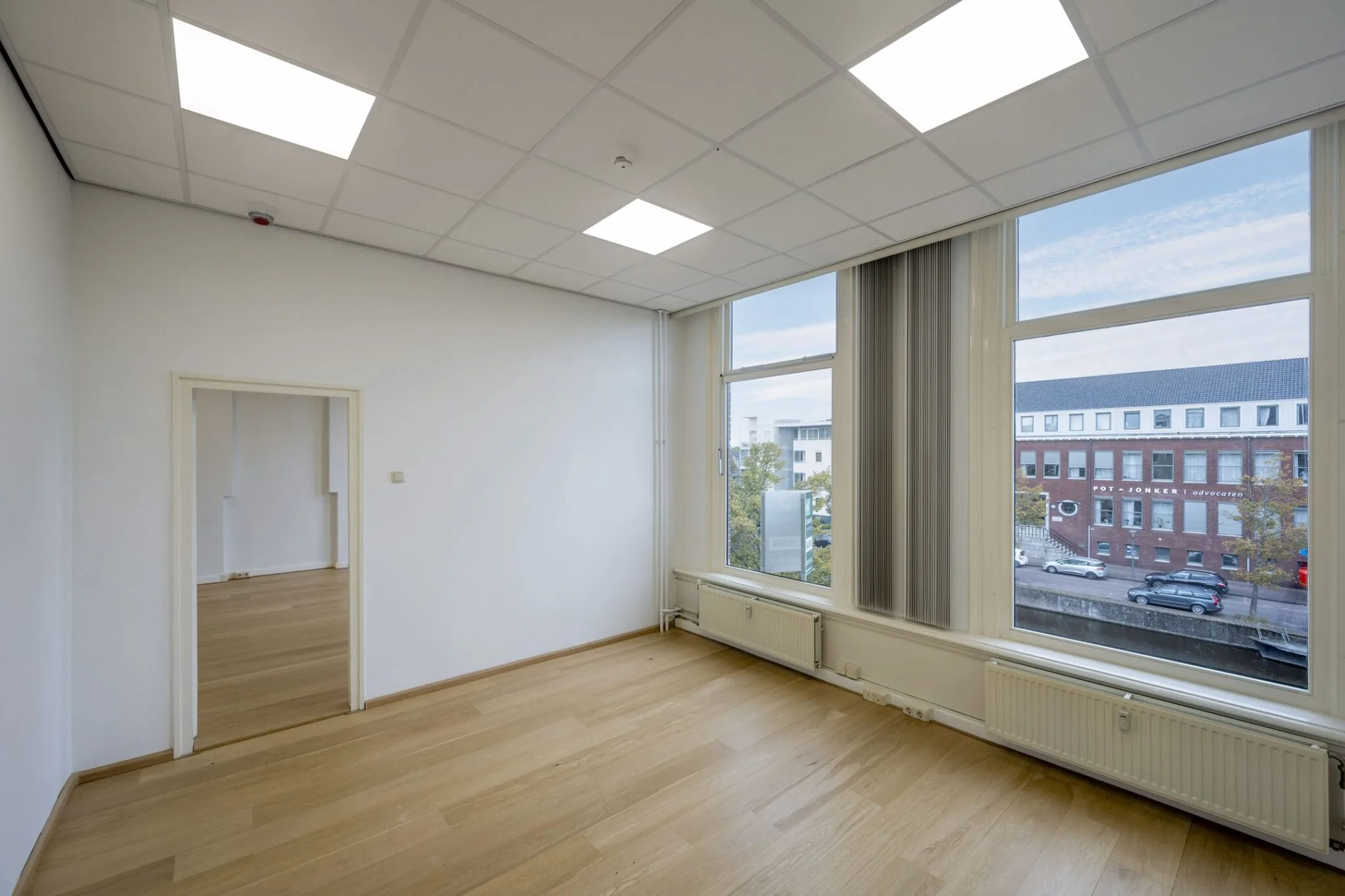 Lichte kantoorruimte met houten vloer en grote ramen aan de Nieuwe Gracht 45-47 in Haarlem.